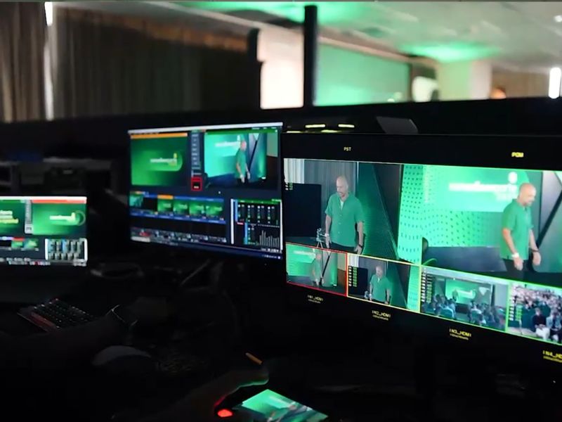 Equipe técnica operando transmissão ao vivo de evento com câmeras profissionais e monitores de streaming, fotografia realista