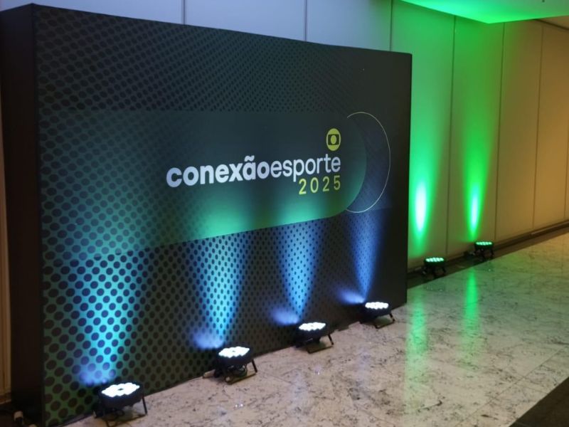 Backdrop de evento com estrutura de box truss e identidade visual de marca, fotografia profissional em ambiente de festa corporativa